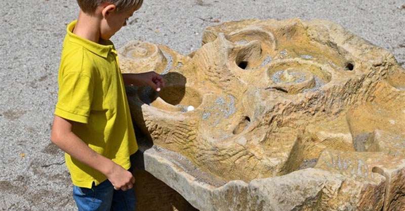 Auf einem Spielplatz spielt ein Kind mit der Murmelbahn