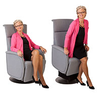 Fitform Wellness Premium Sessel als Drehsessel mit hellgrauem Bezug. Sitzende Frau nutzt die Aufstehhilfe, mit der die Sitzfläche zum Aufstehen angehoben und nach vorn gekippt wird.