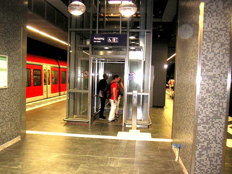 Der Leitstreifen führt zum Aufzugtaster, der an der Stele gut auffindbar ist. Durch die Stützenstellung ist der Raum sehr knapp, der Leitstreifen quer über den Bahnsteig liegt deshalb eigentlich zu dicht am Aufzug.