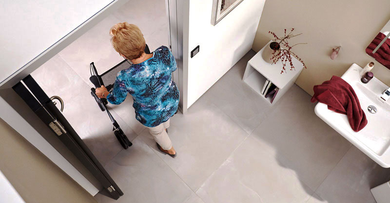 Frau mit Rollator geht durch geöffnete Raumspartür