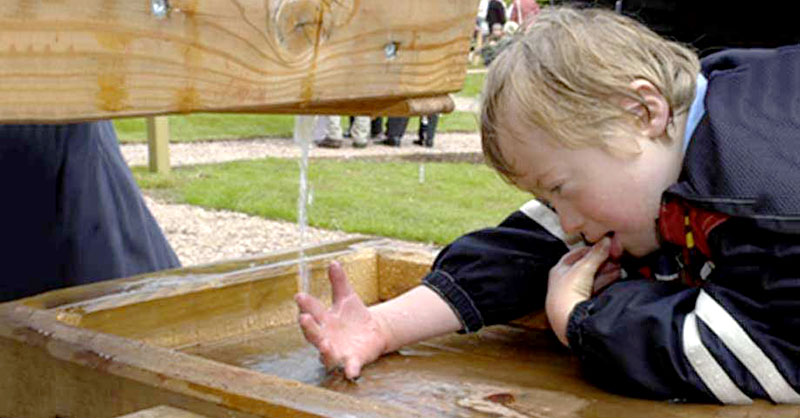 Kind spielt an Wasserrinne