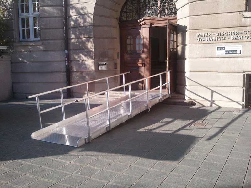 Rampe führt über die Treppe zum Eingang einer Schule