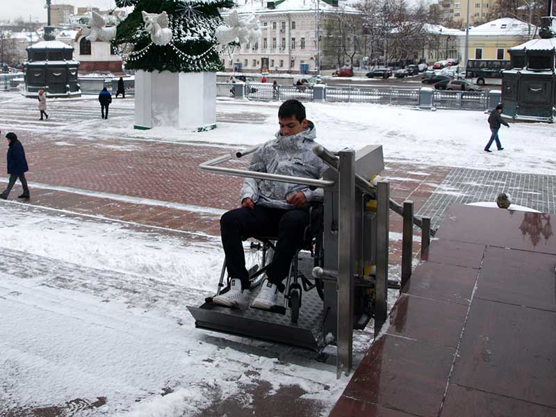 Junge im Rollstuhl auf dem Plattformlift im Winter