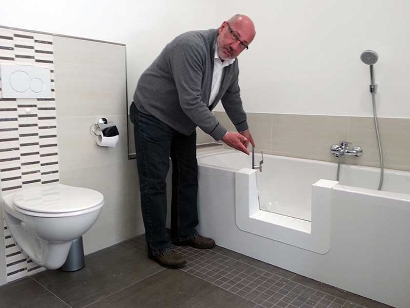 Berater erklärt die Funktion einer Badewannetür am Beispiel vor Ort.