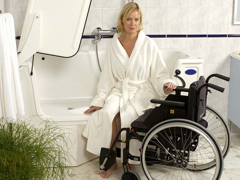 Frau rutscht vom Rollstuhl auf den Rand der Liegebadewanne