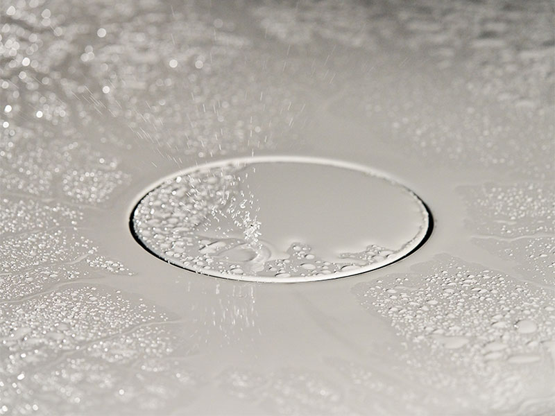 Wassertropfen auf dem Abfluss einer Duschtasse