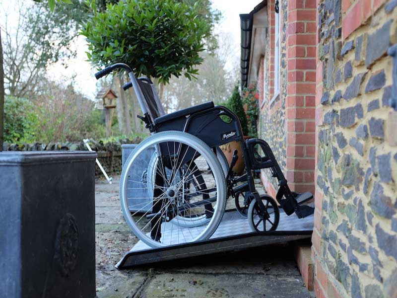 Rollstuhl auf fester AD-Schwellen-Rampe an einem Hauseingang