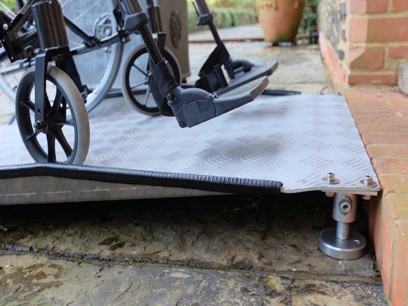 Rollstuhl auf höhenverstellbarer AD-Schwellen-Rampe an einem Hauseingang