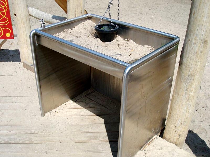 mit dem Rolli unterfahrbarer Tisch auf einem Spielplatz mit Sand gefüllt