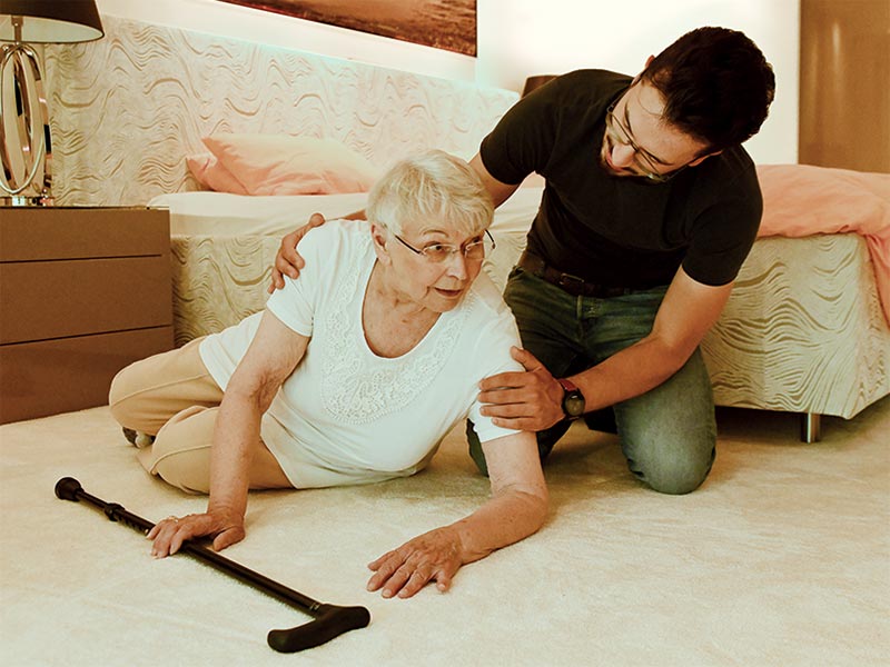 Ein Mann hilft einer Seniorin, die im Schlafzimmer gestürzt ist
