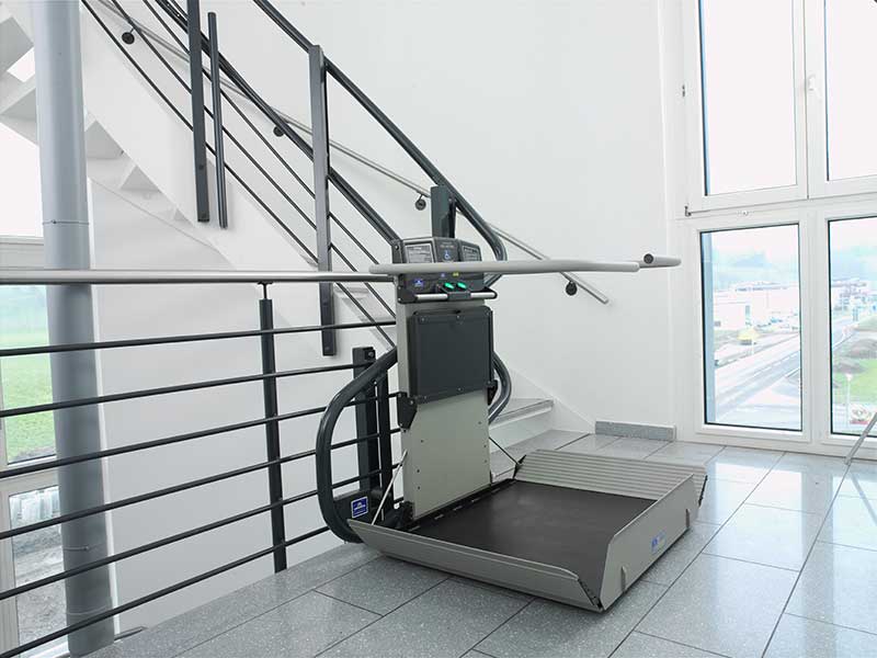 Treppenplattformlift für Rollstuhl mit Auffahrklappe am Treppenabsatz in einem öffentlichen Gebäude