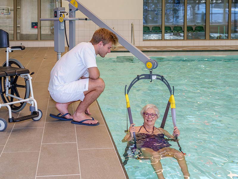 Im Schwimmbecken sitzt eine Frau im Schwimmbadlifter