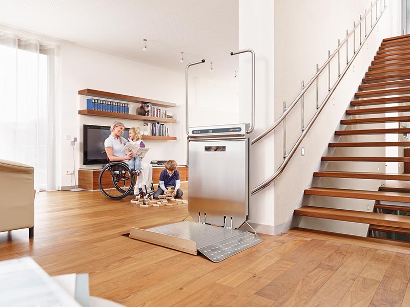 Wohnzimmer mit Frau im Rollstuhl, Kind, Treppe und Plattformlift