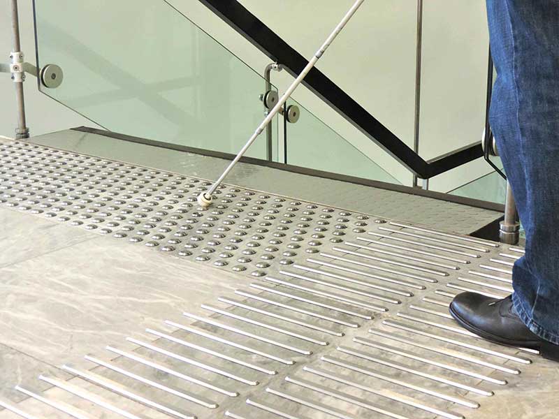 Bodenleitsystem aus Stahlrippen und Noppen am oberen Ende einer Treppe