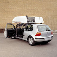 Rolli-Dachbox zieht einen Rollstuhl ins Innere der Box Rollstuhl wird in die Dachbox gezogen