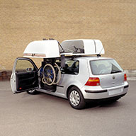 Rollstuhl hängt neben dem Fahrzeug an der Dachbox