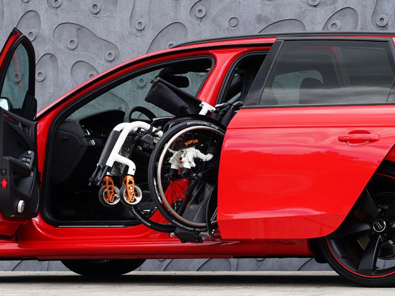 E-Rollstuhl wird in Audi Limousine seitlich hinter Fahrersitz verstaut