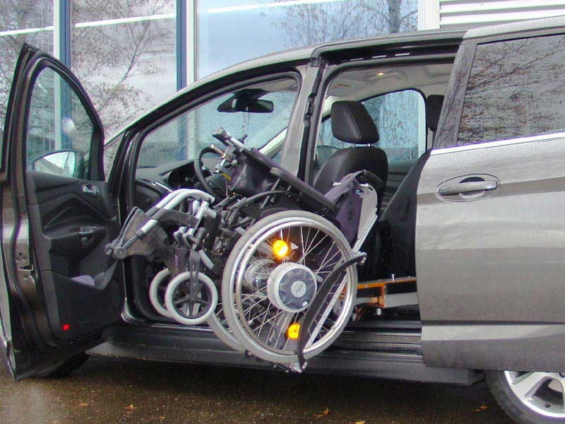E-Rollstuhl wird in Ford van seitlich hinter Fahrersitz verstaut