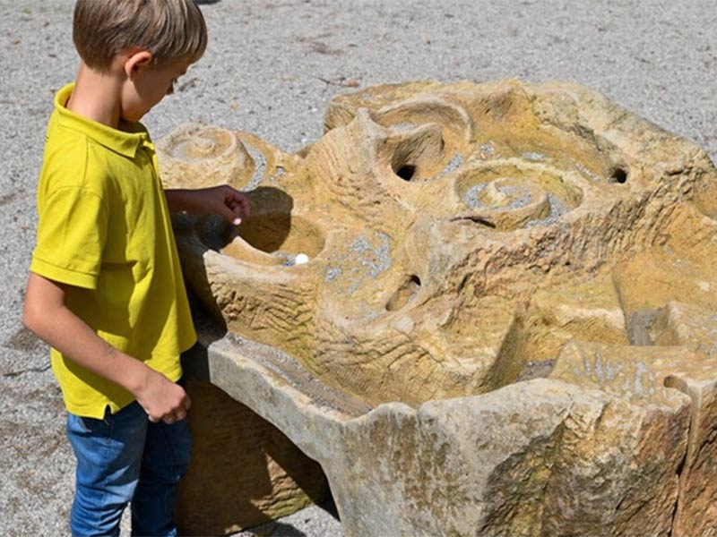 Auf einem Spielplatz spielt ein Kind mit der Murmelbahn