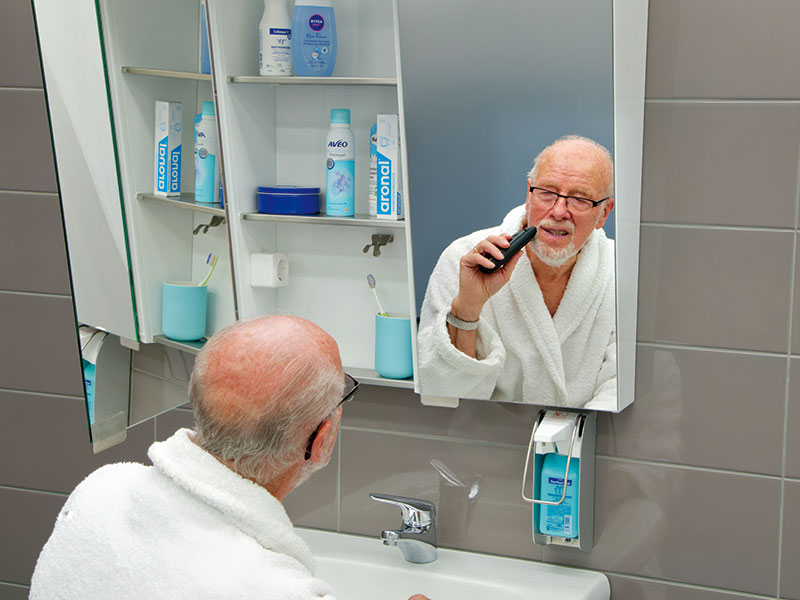 Mann rasiert sich im Sitzen vorm Spiegel