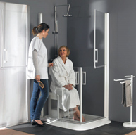 Flexibles Duschsystem mit geteilter Doppeltür und Rampe Pflegekraft vor geöffneter Dusche während zu pflegende Person auf Hocker in der Dusche sitzt