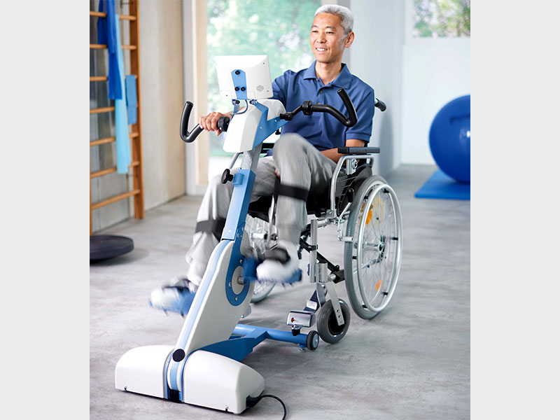 Mann im Rollstuhl trainiert seine Beine im Therapieraum