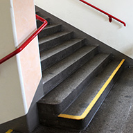 kontrastreiche Handläufe und Stufenmarkierung an einer Treppe in einer Schule