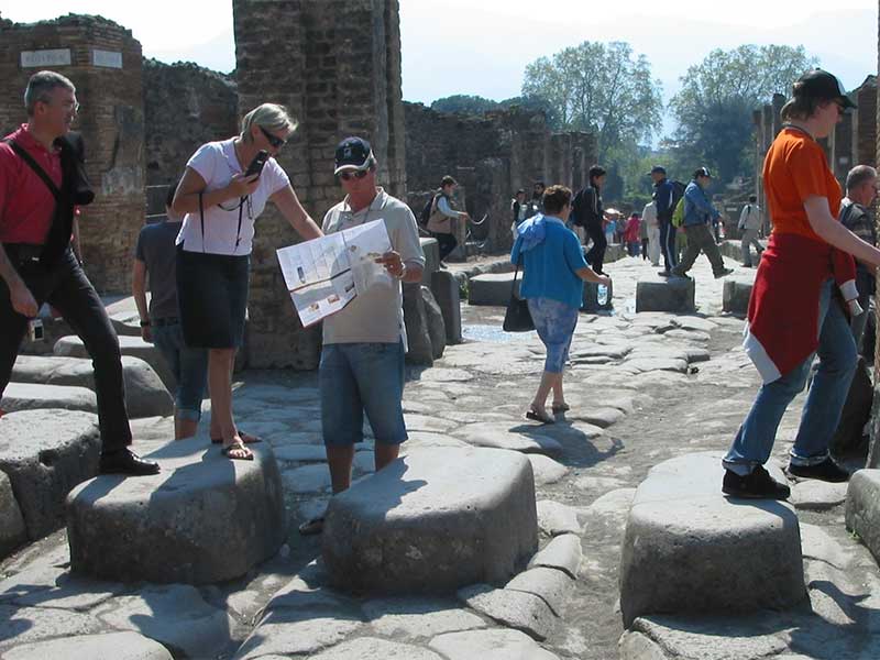 Touristen begehen einen erhöhten Zebrastreifen aus der Antike in Pompeji