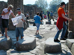 Touristen begehen einen erhöhten Zebrastreifen aus der Antike in Pompeji