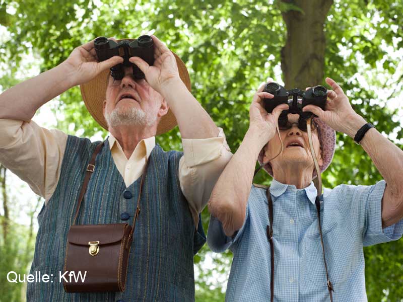Zwei Senioren mit Ferngläsern in der Hand schauen in den Himmel