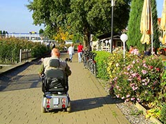 barrierefreie Uferpromenade Rollstuhlfahrer fährt eine barrierefreie Uferpromenade entlang