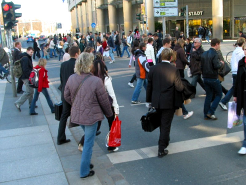 Viele Fußgänger überqueren eine gesicherte Fußgängerüberquerung in der Dresdener Innenstadt