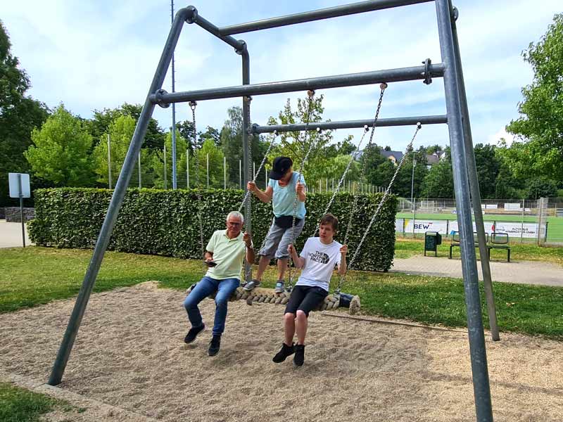 1 Erwachsener und 2 Kinder auf einer Schaukel