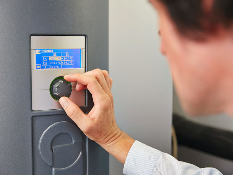 Ein Energieberater der KfW beim Kontrollieren der Heizungsanlage eines Niedrigenergiehauses